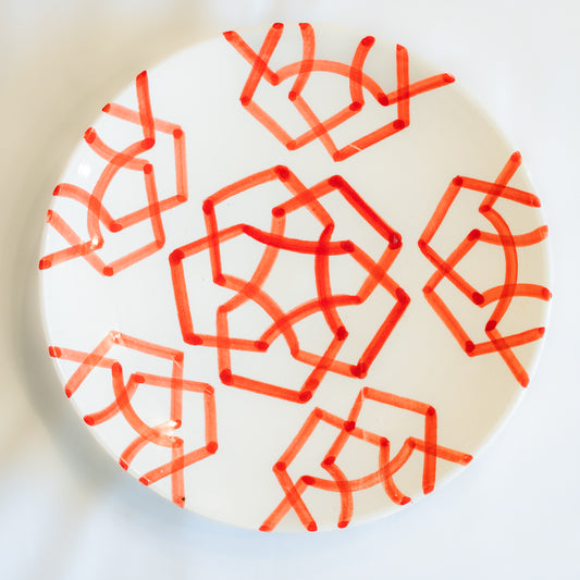 Assiette en céramique blanche peinte à la main avec des motifs géométriques rouges, illustrant l'authenticité et l'éclat de l'art marocain.