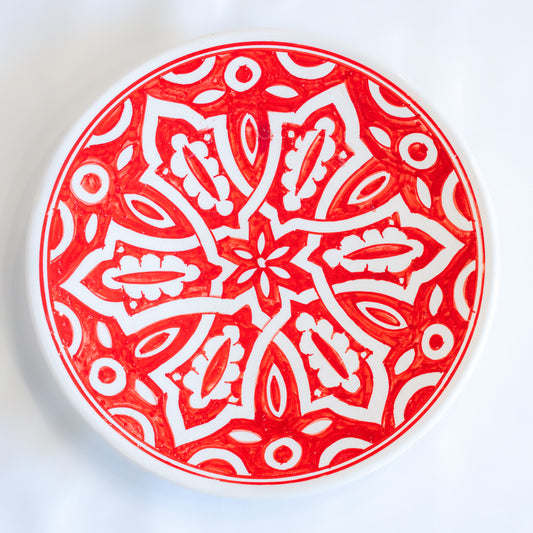 Assiette en céramique rouge et blanc, fabriquée à la main au Maroc, reflétant une atmosphère d'authenticité.