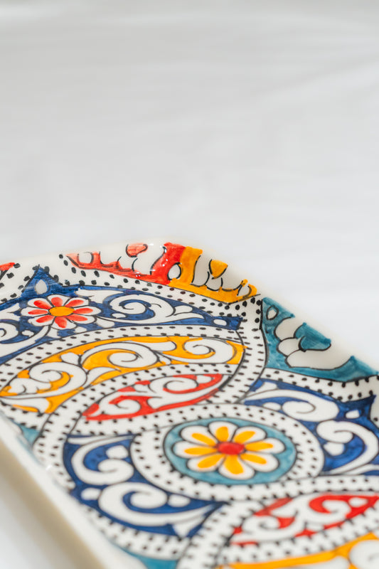 Plat à cake en céramique blanche avec des motifs arabesques colorés, reflet de l'artisanat du Maroc.