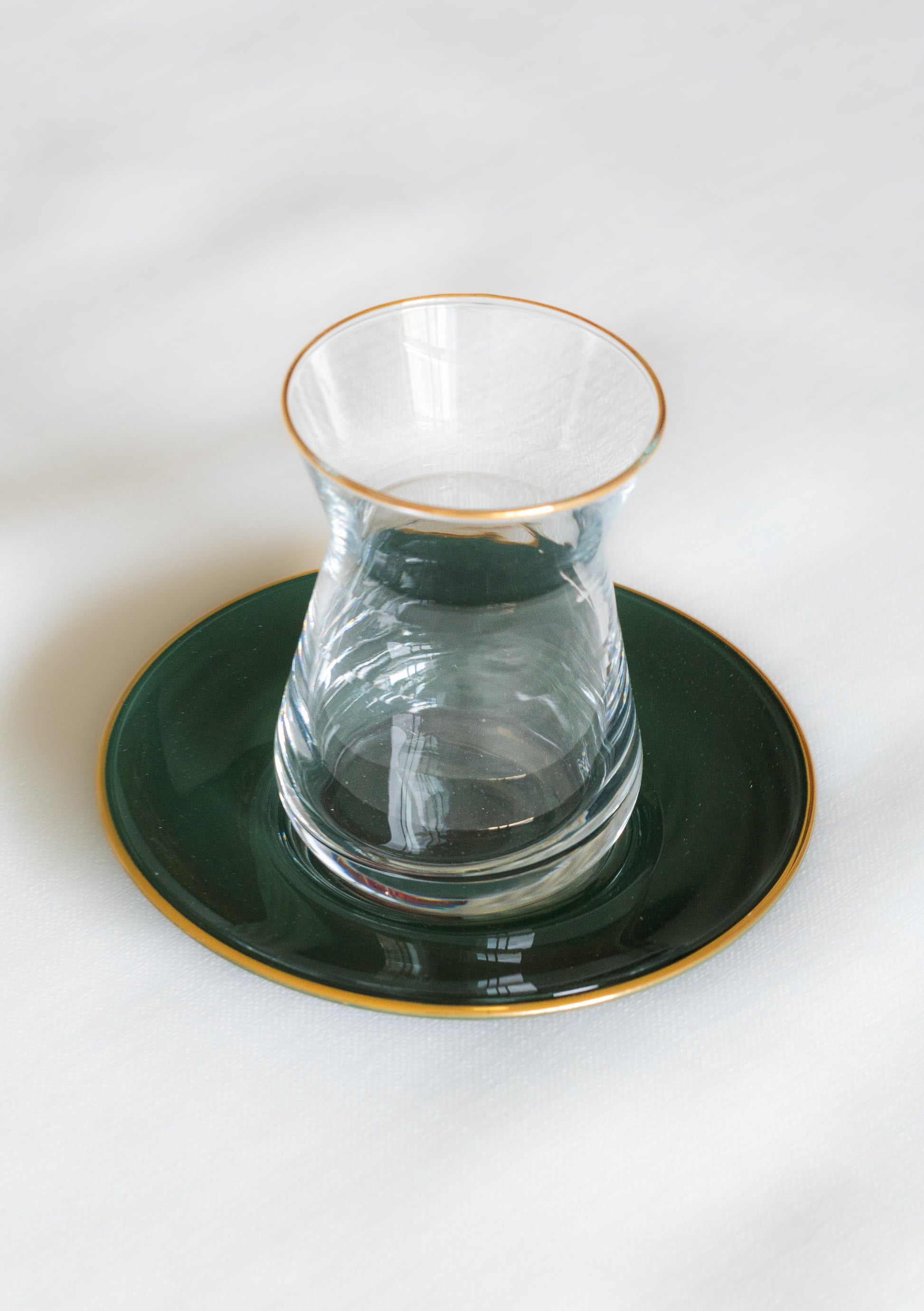 verres à the couleur vert du Maroc avec une bordure doree poses sur des soustasses assorties pour une atmosphere authentique