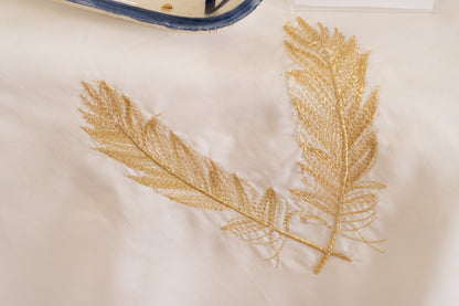 Nappe blanche ornée de motifs dorés évoquant l'atmosphère authentique et l'éclat du Maroc